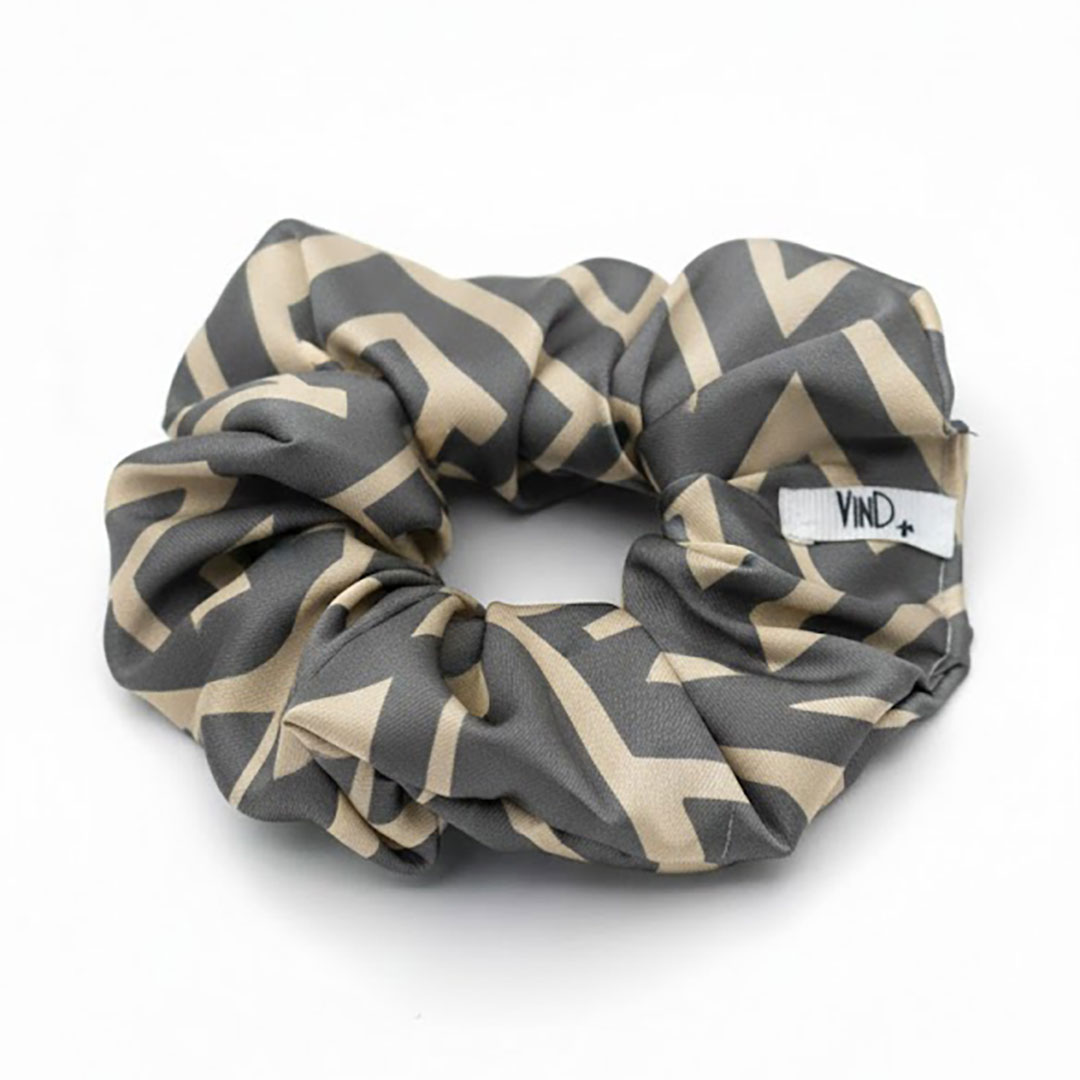 LIVIA GREY LATTE εμπριμέ σατέν scrunchie (λαστιχάκι μαλλιών) με geometric lines pattern σε grey και latte αποχρώσεις. Minimal και κομψό αξεσουάρ μαλλιών με απαλή υφή και σταθερό κράτημα.